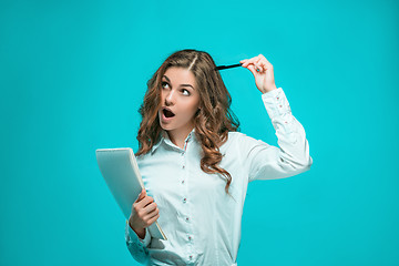 Image showing The thoughtful young business woman with pen and tablet for notes on blue background