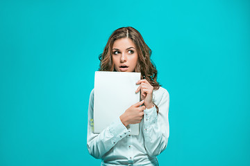 Image showing The thoughtful young business woman with pen and tablet for notes on blue background