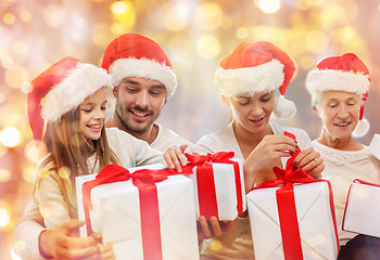 Image showing happy family in santa hats with gift boxes