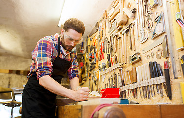 Image showing carpenter working with plane and wood at workshop