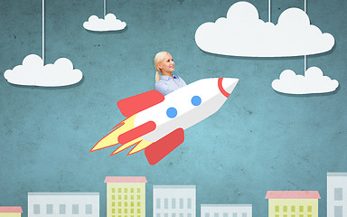 Image showing businesswoman flying on rocket above cartoon city