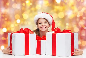 Image showing smiling girl in santa hat with christmas gifts