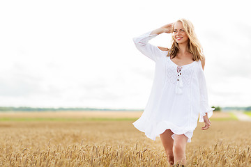 Image showing smiling young woman in white dress on cereal field