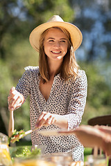 Image showing happy young woman serving dinner at summer garden