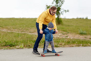 Image showing happy father and little son on skateboard