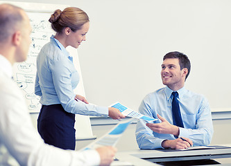 Image showing smiling woman giving papers to man in office