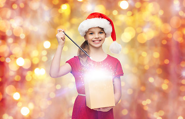 Image showing girl in santa hat with gift box and magic wand