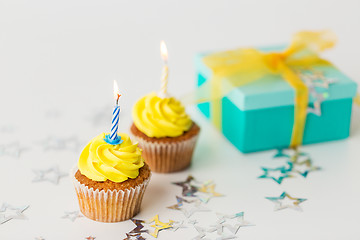 Image showing birthday cupcakes with burning candles and present