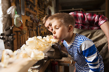 Image showing father and little son with wood plank at workshop