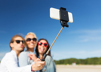 Image showing women with selfie stick and smartphone on beach