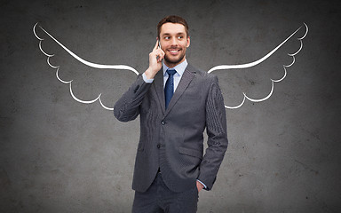 Image showing businessman with angel wings calling on cellphone