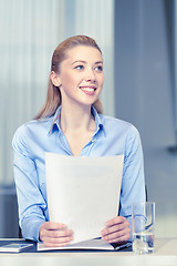 Image showing smiling woman holding papers in office