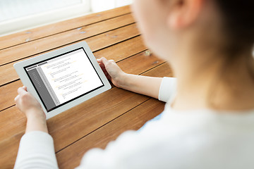 Image showing close up of woman with tablet pc on wooden table