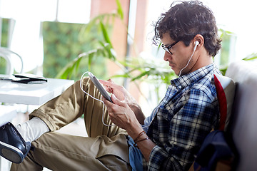 Image showing man with tablet pc and earphones sitting at cafe