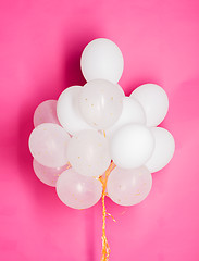 Image showing close up of white helium balloons over pink