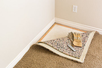 Image showing Gloves and Utility Knife On Pulled Back Carpet and Pad In Room.