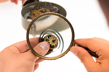 Image showing The male hand with magnifier and clockwork