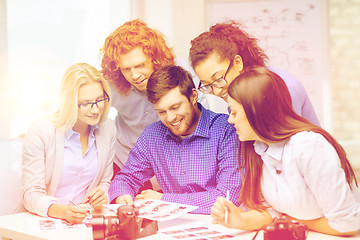 Image showing smiling team with photocamera and images in office