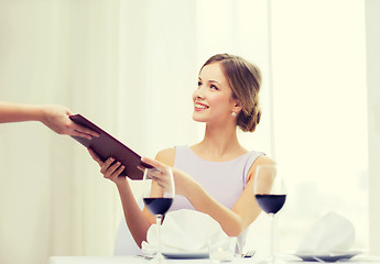 Image showing smiling woman giving menu to waiter at restaurant