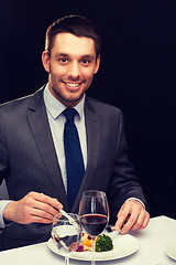 Image showing smiling man eating main course