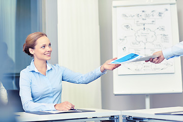 Image showing businesswoman taking papers from someone in office