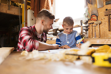 Image showing happy father and son with blueprint at workshop