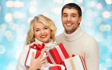 Image showing happy couple in sweaters holding christmas gifts