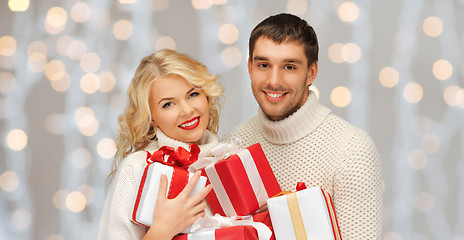 Image showing happy couple in sweaters holding christmas gifts
