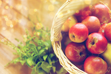 Image showing close up of basket with apples and herbs on table