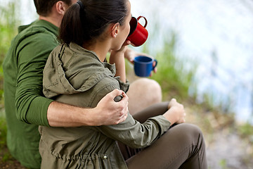 Image showing happy couple with cups drinking in nature