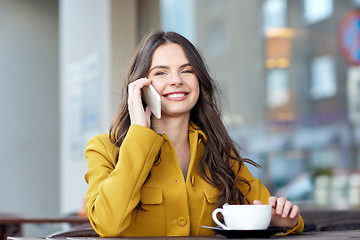 Image showing happy woman calling on smartphone at city cafe