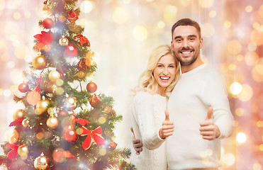 Image showing happy couple showing thumbs up with christmas tree