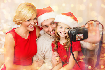 Image showing smiling family in santa helper hats taking picture