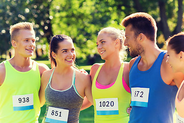 Image showing happy friends or couple with racing badge numbers