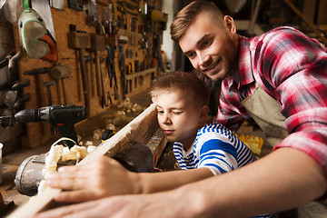 Image showing father and little son with wood plank at workshop