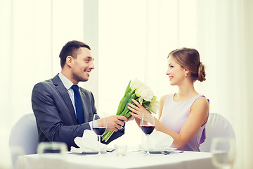 Image showing smiling man giving flower bouquet at restaurant