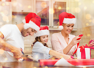 Image showing smiling family in santa helper hats with gift box