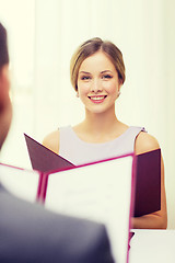 Image showing smiling young woman with menu at restaurant