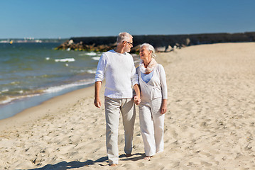 Image showing happy senior couple holding hands on summer beach