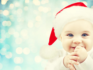 Image showing happy baby in santa hat over blue holidays lights