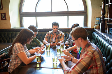 Image showing friends with smartphones and beer at bar or pub