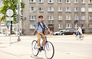 Image showing young hipster man with bag riding fixed gear bike