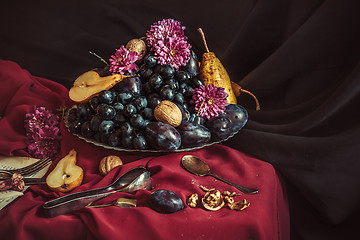 Image showing The fruit bowl with grapes and plums against a maroon tablecloth