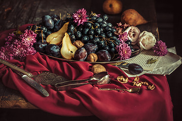 Image showing The fruit bowl with grapes and plums against a maroon tablecloth