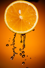 Image showing Orange slice and splash of juice isolated on color background