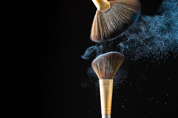 Image showing Beautiful splash after touch of two professional brushes on black background