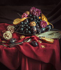 Image showing The fruit bowl with grapes and plums against a maroon tablecloth