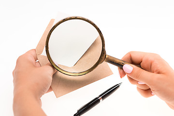 Image showing The female hands with envelope with magnifying glass on white background