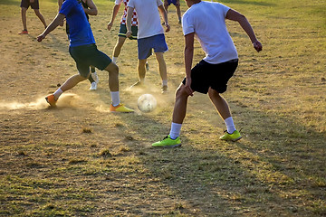 Image showing Young boys playing football game on the sunset