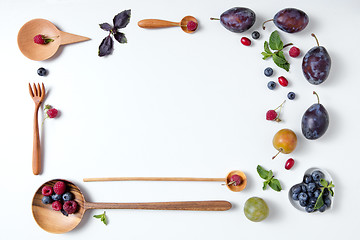 Image showing frame of spoons with berries and plums